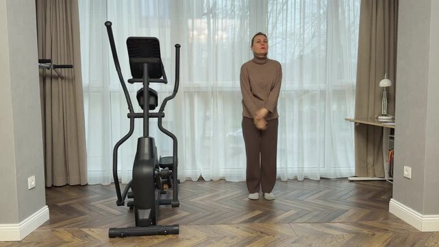 Woman in sportswear lifts knees toward palms in controlled tempo. Home exercise for coordination and balance.