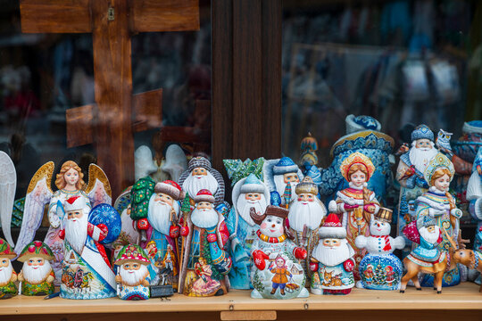 Large collection of hand-painted Russian wooden figurines including Ded Moroz, Snegurochka, snowmen, and angels displayed on market shelf.