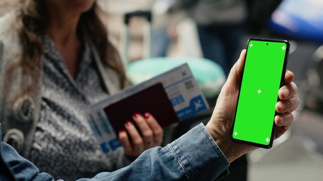 Vertical green screen on phone in hands of elderly traveler sitting at gate, planning itinerary and checking app, highlighting modern retirement lifestyle.