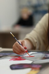 Painting hand — Close-up of hand painting with brush, red paint stroke on canvas, creative process © a_frameoflife