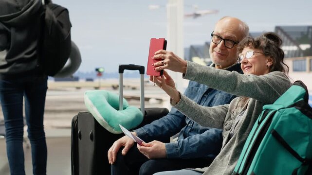 Elderly man and woman taking pictures while waiting for boarding time, excited about traveling in golden years of retirement, highlighting memories in later life, adventure and old age.