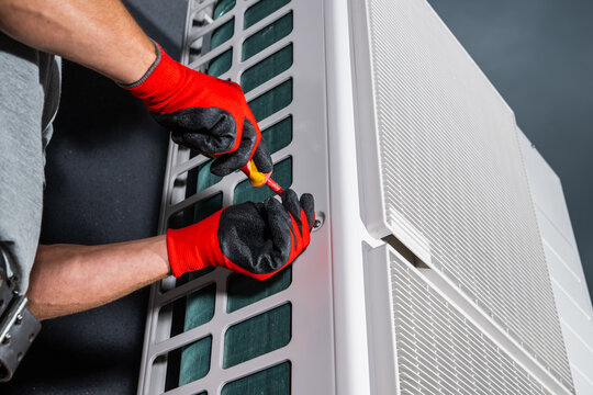 Technician using a screwdriver on an outdoor HVAC unit