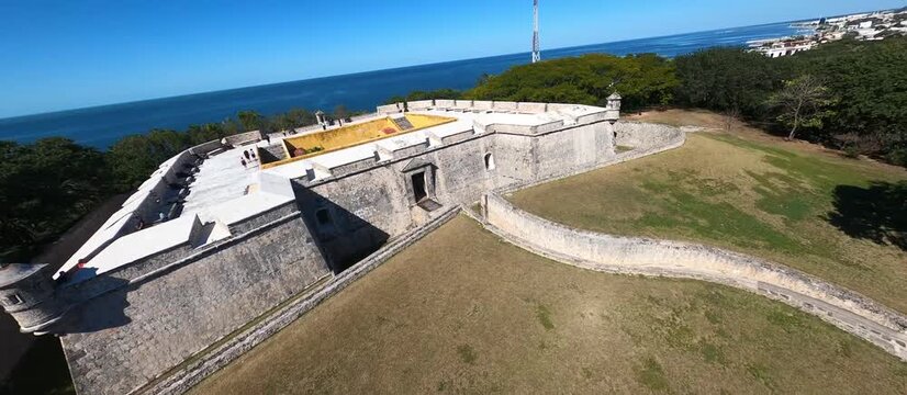 FPV drone flight over colonial fortress and walled city, historic bastions and Caribbean coastline, aerial view of preserved heritage architecture and waterfront, cinematic historical destination foot