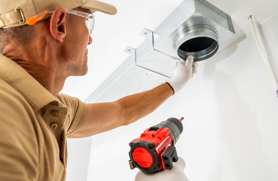 Technician fitting a ceiling ventilation duct connector