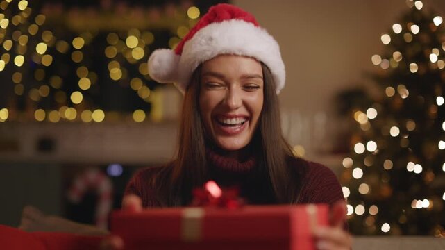 Woman in Santa hat reacting excitedly to Christmas gift at home, 4K
