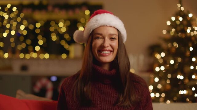 Happy woman in Santa hat giving wrapped Christmas gift toward camera, 4K