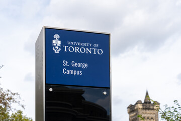 Obraz premium Toronto, Ontario, Canada - September 16, 2026: A campus directional sign with historic stone buildings in the background at the St George Campus of the University of Toronto in downtown Toronto, Ontar