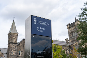 Obraz premium Toronto, Ontario, Canada - September 16, 2026: A campus directional sign with historic stone buildings in the background at the St George Campus of the University of Toronto in downtown Toronto, Ontar