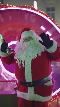 Santa Claus Waving Hand and Ringing Bell on Festive Illuminated Display
