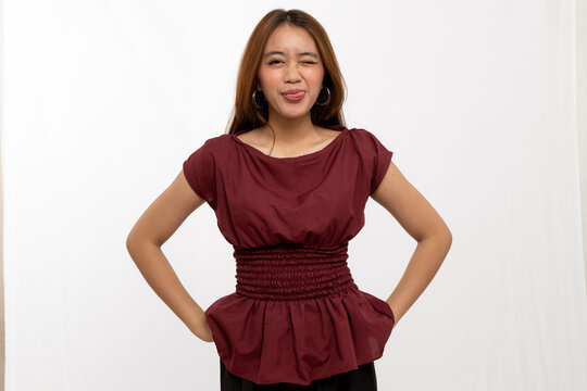 Young Woman Making Playful Face Wearing Wine Colored Blouse with Hands on Hips Against White Background