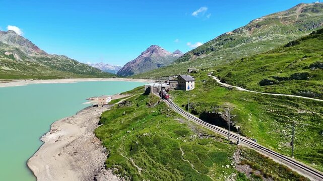 red swiss train in Swiss Alps. famous Lake Bianco on way to St. Moritz. Switzerland summer tourism.