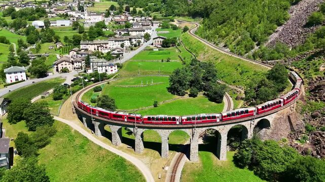 Drone Switzerland 4k.  train on way to St. Moritz. Brusio spiral viaduct, stone spiral railway viaduct on the Bernina Railway. Swiss Alps in summer. 
