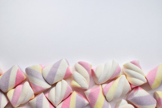 Multi-colored marshmallows on white background. Background or texture of colorful blue and pink marshmallows. Cope space.
