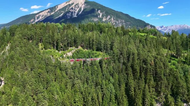 Aerial drone Switzerland. Glacier Express red swiss train in Swiss Alps. Rhaetian Railway scenic route Zermatt to St. Moritz. Viaduct bridge. Switzerland summer tourism.