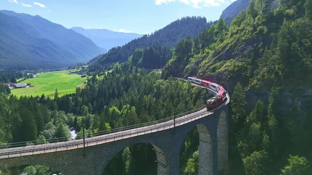 Drone Switzerland 4k. Red swiss train on viaduct bridge. Landwasser, Swiss Alps. scenic route Zermatt to St. Moritz. Switzerland summer tourism.
