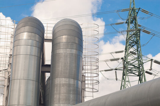 A close-up of a pipeline and a power transmission tower against a blue sky