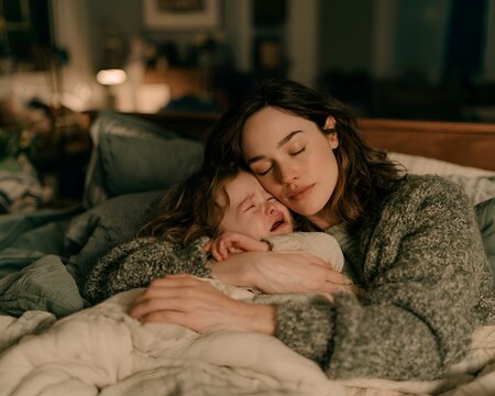 Mother comforting her crying baby in bed at night with gentle embrace