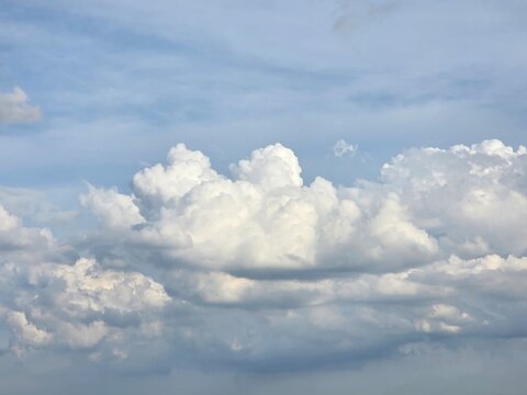 Cumulus Clouds in Blue Sky: Fluffy white cumulus clouds drift lazily across a clear blue sky, casting soft shadows and creating a sense of serene vastness.