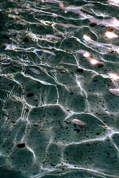 A close-up view of the detailed texture of the water in a pool or fountain, illuminated by the sun's rays
