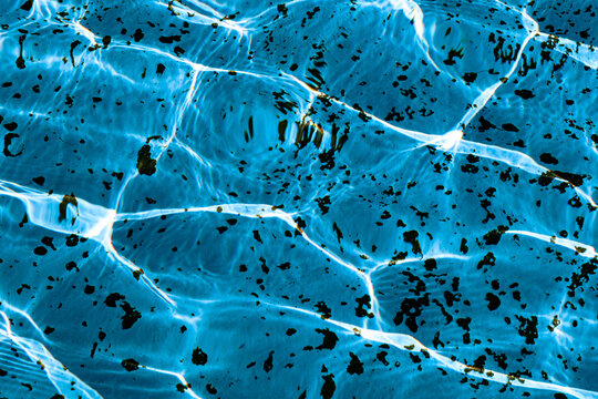 A close-up view of the detailed texture of the water in a pool or fountain, illuminated by the sun's rays
