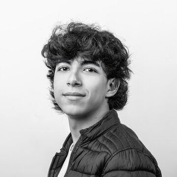 Teen boy with curly hair smiling in black and white portrait