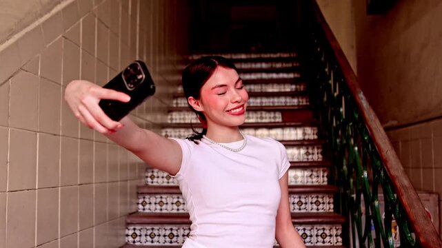 Young Latina woman taking selfies indoors with a fan