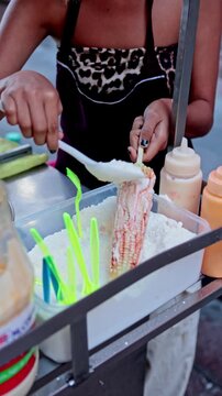 Street vendor preparing a traditional Mexican grilled corn elote