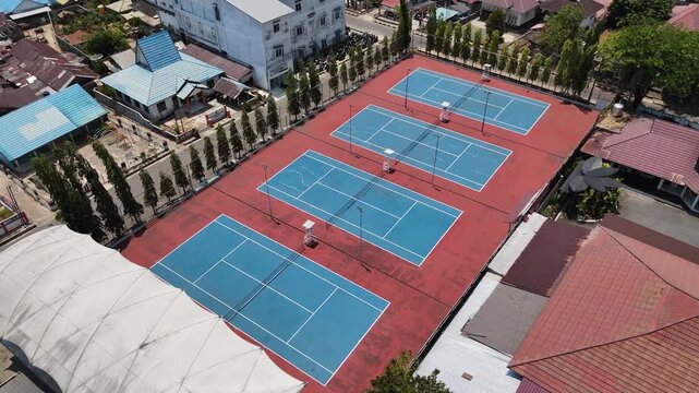 High angle view showing blue tennis courts situated within a neighborhood in Indonesia