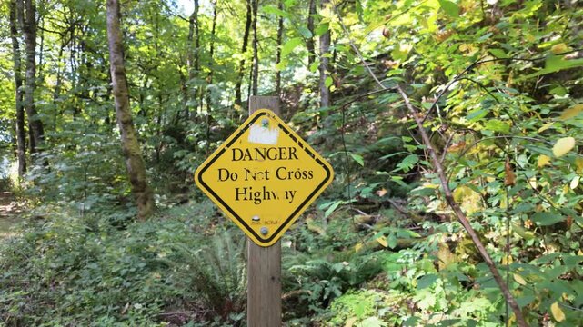 Langford, British Columbia, Canada - September 16, 2026: Yellow BC Parks Danger Do Not Cross Highway Warning Sign in Goldstream Provincial Park