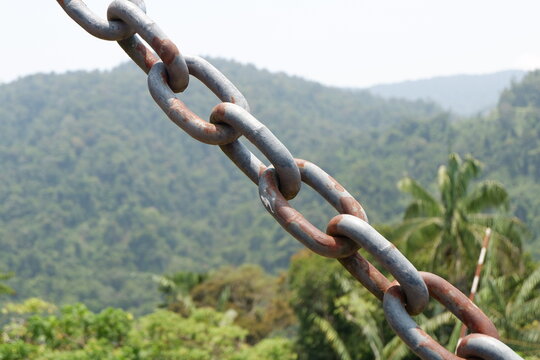 Rusty chain link hanging on a wooden bridge.