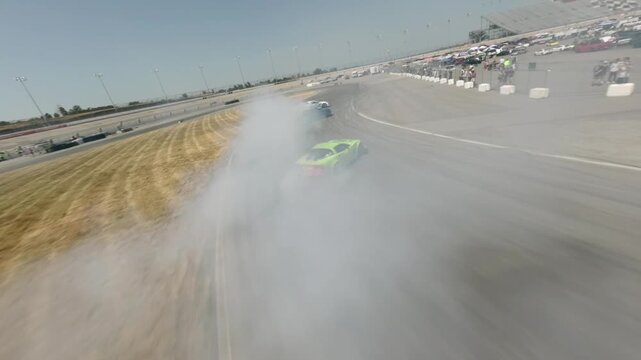 High-speed FPV drone following motorsport drifting in tandem with burning tires on a sunny day