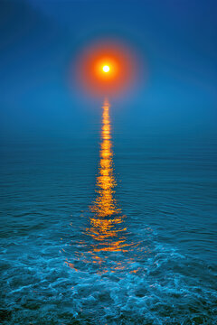 Gleaming sunpath on deep blue ocean water with dramatic mood