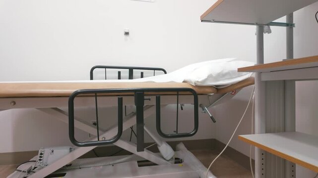 Adjustable Medical Examination Table with Rails and Pillow in Clinic Room