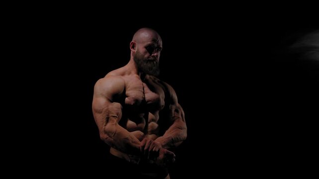 A male bodybuilder poses in shorts, showing off his muscles. Close-up of his chest and abs.