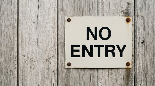 Weathered metal no entry sign attached to rustic gray wooden planks with visible rusted iron bolts
