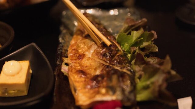 Eating Grilled Saba Mackerel With Wooden Chopsticks in Japanese Restaurant