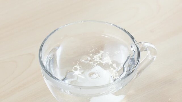 Dropping Sugar Cube into Glass Cup of Water with Tongs