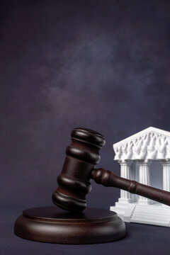 Vertical composition of a judge gavel on a sound block and a courthouse model. Judicial rulings, legal authority, constitutional law, and court decisions concept.