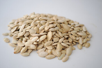 Obraz premium Dry pumpkin seeds placed in a neat pile on a plain surface