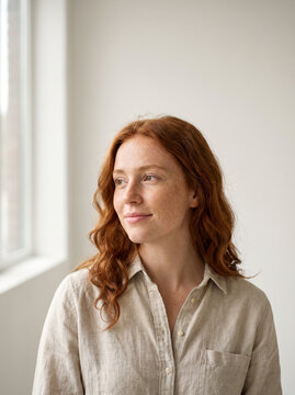 Young redhead woman with freckles embraces natural beauty