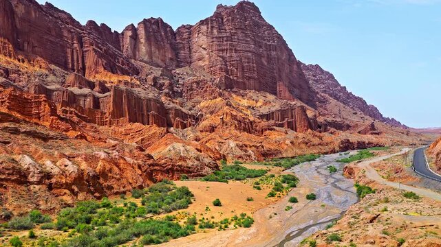 Drone view of a dry riverbed winding through a red sandstone canyon along the Duku Highway in Xinjiang, China
