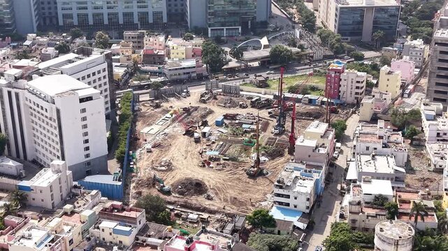 Urban construction site with cranes and piling machinery amid city buildings real estate development