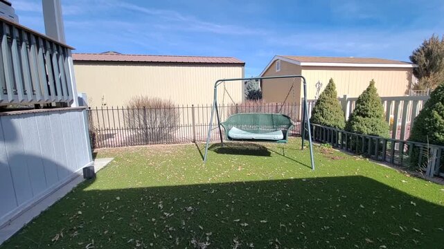 Sunny backyard with a swing set and trimmed hedges