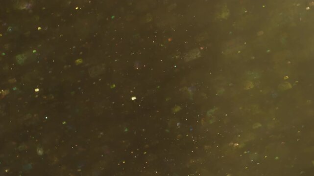 Bokeh leak twirl. Flare glimmer. Yellow gray whirl mixing flow. Golden shimmering light color particles on dark abstract background.