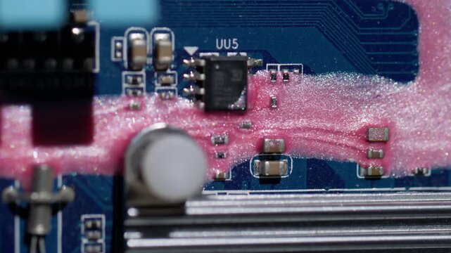 Chip scheme. Ink trickles. Shimmering pink fluid pouring on blue motherboard texture. Color electronics system defocused background.