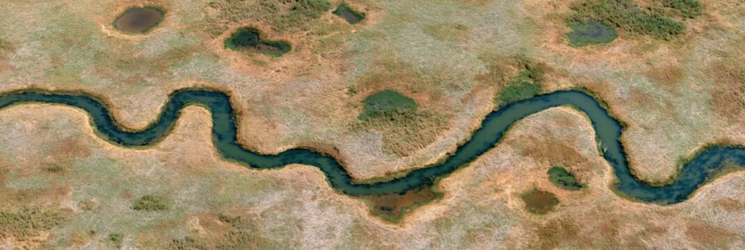 Aerial view of sinuous river winding through dry wetlands landscape