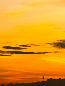 Silhouetted Clouds Against Bold Orange Sunset Gradient Sky