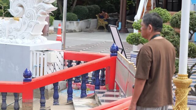 Man visiting Thai Buddhist temple for making merit and sightseeing, tourist exploring traditional temple architecture in Thailand, stock footage video.