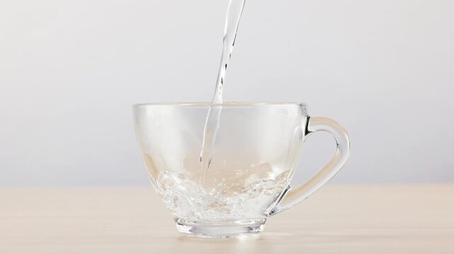 Fresh Water Pouring into Clear Glass Cup on Wooden Table