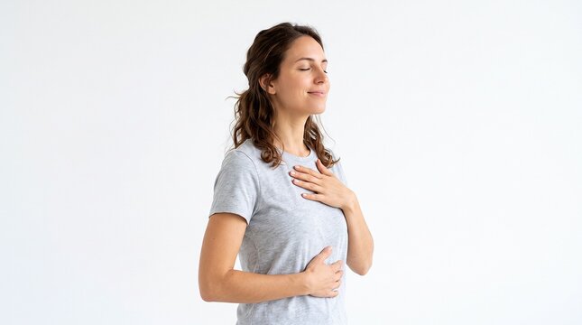 Mulher com olhos fechados e m&atilde;os no peito e abd&ocirc;men, respirando fundo com express&atilde;o serena e calma